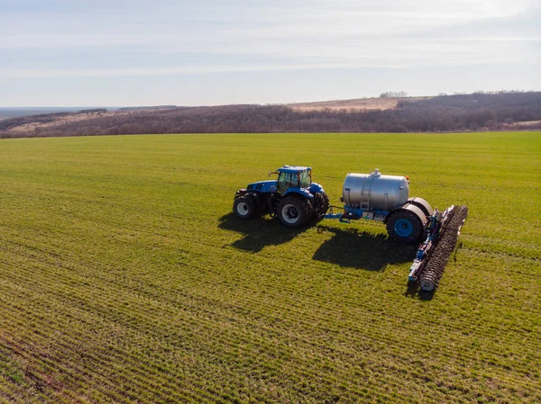 A introdução fertilizantes minerais líquidos no solo com trator trigo de inverno — Fotografia de Stock