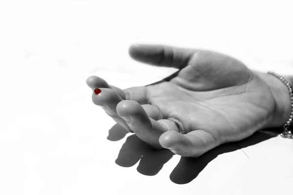 Siyah ve beyaz bir parmak ile kırmızı kan damlası