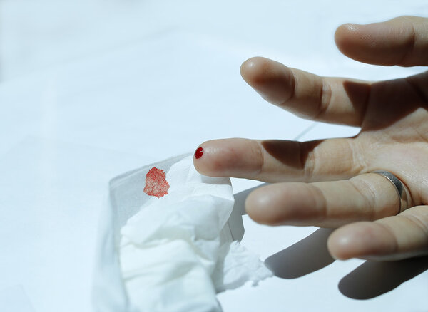 A finger with red blood drop