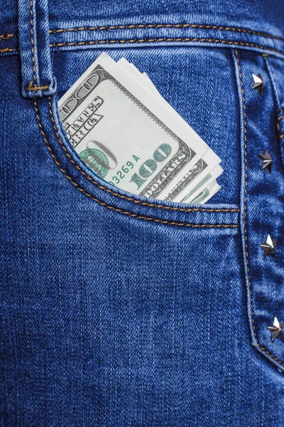 З передньої кишені жіночих синіх джинсів висить купюра вартістю сто доларів. Американська валюта. Вибіркові гроші за невеликі витрати. Заробляю гроші. Копіювальний простір, елемент дизайну. — стокове фото