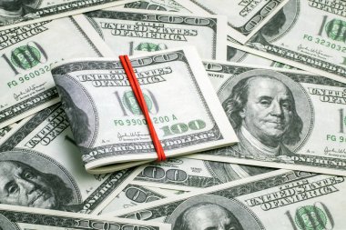 Yüzlerce dolarlık banknotlardan toplanmış kırmızı lastik bantla bağlanmış bir deste Amerikan parası. İş, finans, ticaret, kâr, para geçmişi