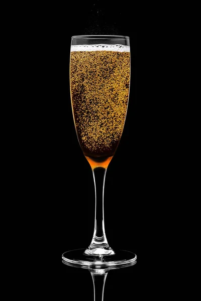 A single champagne glass filled with golden bright sparkling wine with foam and bubbles isolated on a black background. Design element, clipping path. — Stock Photo, Image