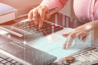 Ofisteki muhasebeci kız belgelerdeki verilere bakıyor ve hesap makinesi ile kontrol ediyor. Pazar ve kar analizi, vergilerin ve giderlerin hesaplanması, finansal optimizasyon kavramı