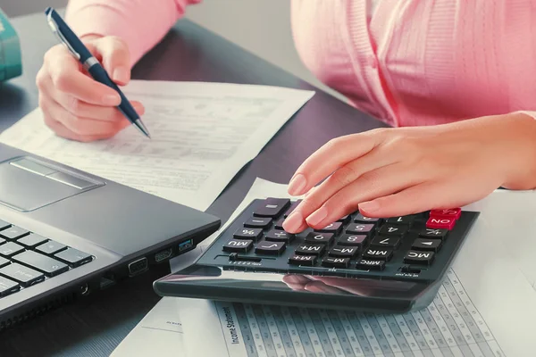 Close up of the hands of a female accountant who uses a calculator to check bills. Profit analysis, calculation of taxes and payments, business concept — Stock Photo, Image