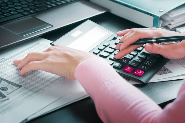 Female accountant in office draws up annual report using income table and calculator. Profit analysis, calculation of taxes, expenses and payments, saving money and budget concept — Stock Photo, Image