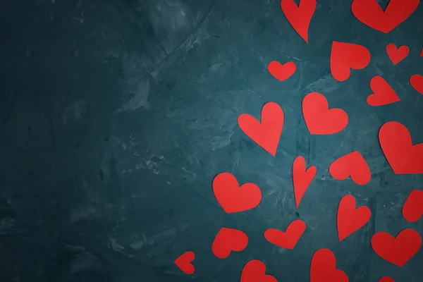 Красные сердца различных форм, вырезанные из бумаги, разбросаны на абстрактном текстурированном голубом фоне с копировальным пространством . — стоковое фото