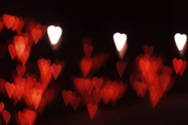 Luces rojas y blancas borrosas abstractas en forma de corazones. Iluminación festiva callejera desenfocada. Día de San Valentín, boda, fondo de amor —  Fotos de Stock