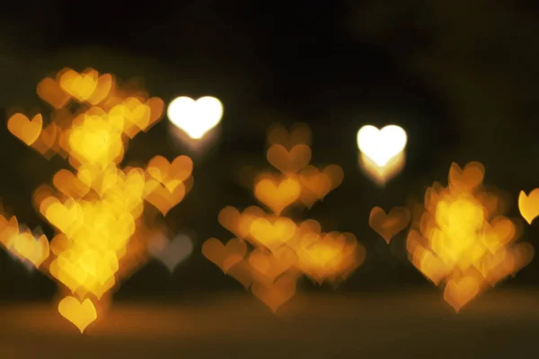 Luces blancas y doradas borrosas abstractas en forma de corazones. Iluminación festiva callejera desenfocada. Día de San Valentín, boda, fondo de amor —  Fotos de Stock