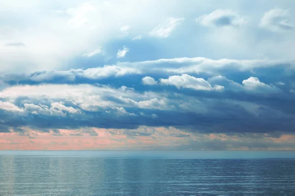 Hermosas nubes cúmulos texturizadas dramáticas al amanecer sobre un mar tranquilo — Foto de Stock