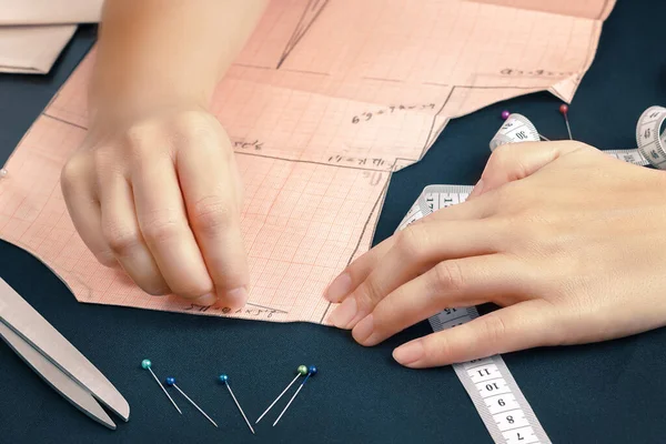 Profesyonel bir kadın terzinin iğneleriyle kumaşa kıyafet kalıbı ekleme sürecinin yaklaşması.