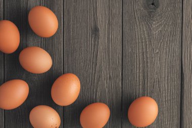 Kırsal ahşap bir arka planda fotokopi alanı olan sekiz kahverengi tavuk yumurtasının üst görüntüsü.