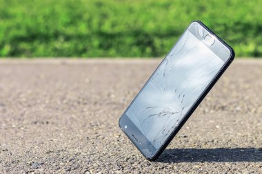 Black modern smartphone falls on the asphalt at the corner of the screen. A cell phone with a cracked, smashed, broken screen with copy space. clipart