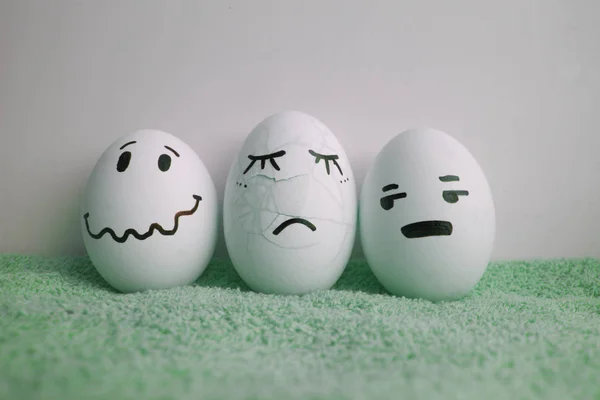 Eggs with faces. Crashed and cracked on a green