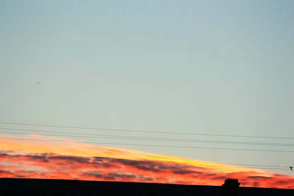 Puesta de sol sobre la casa. Nubes rojas — Foto de Stock