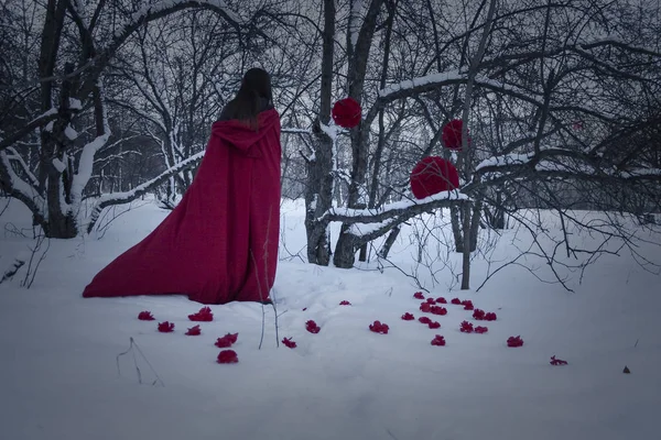 Halloween. Girl witch in red on the snow. Witchcraft