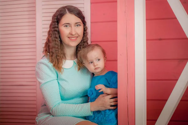 Baby und Mama liegen sich in den Armen. Mädchen im blauen Kleid — Stockfoto
