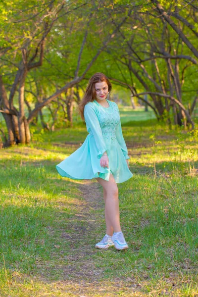 Mooi en aantrekkelijk meisje in een blauwe jurk op een achtergrond van — Stockfoto