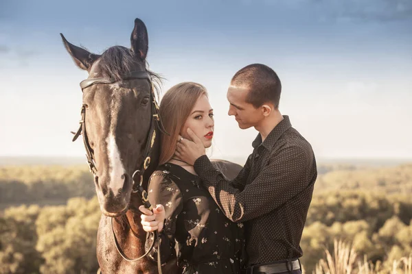 A guy and a girl on a walk. Horse ride. Black horse and lovers