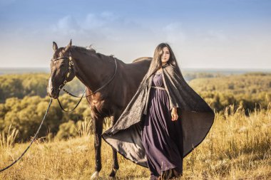 Siyah bir atla yürüyen esmer kız. Çekici bir kız. Yaz gezisi. Macera sevinci