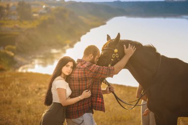 Esmer kız ve siyah atlı sakallı vahşi adam. Seksi bir çift. Yaz gezisi. Aşk hikayesi.
