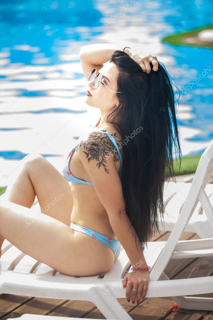 Sexy brunette in a bikini with long black hair. Sunglasses