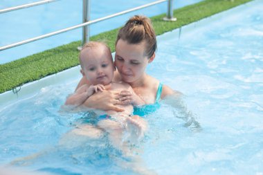 Anne ve bebek havuzda dinleniyor.