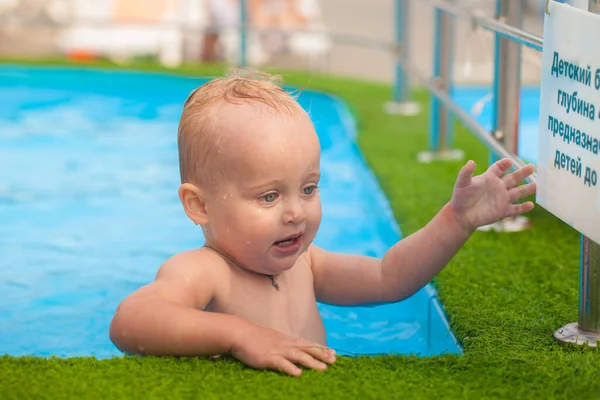 明るい草の縁を持つ紺碧のプールの笑顔の子供 — ストック写真