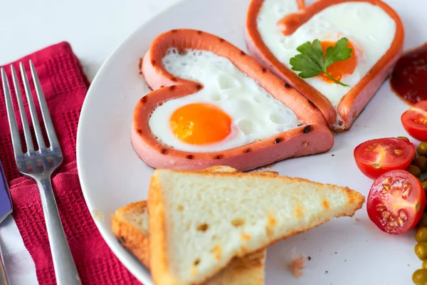 Heart shaped sausages with fried eggs — Stock Photo, Image