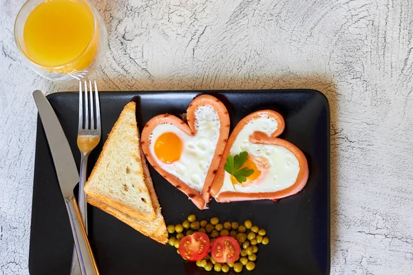 Sevgililer günü - bir kalp ve sosis, domates siyah plaka şeklinde kızarmış yumurta kahvaltı — Stok fotoğraf