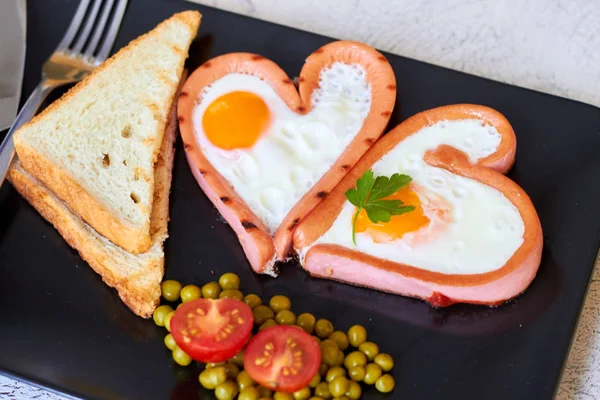 Fried egg on the pan in the wurstel sausage shape of heart — Stock Photo, Image