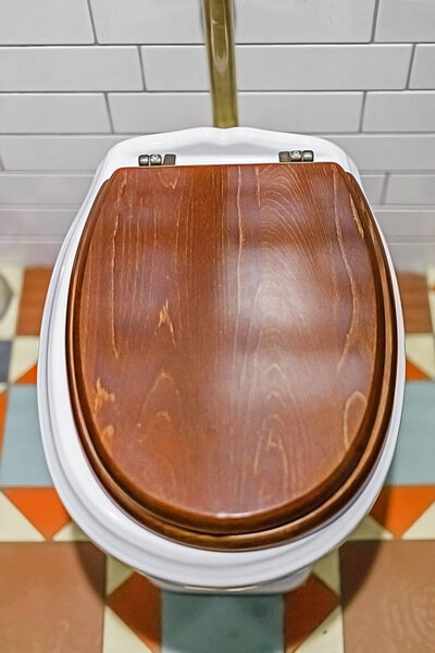 Toilet bowl with wooden cover. The view from the top