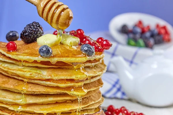 Pancakes with berries and butter. Spoon dripping honey. — Stock Photo, Image