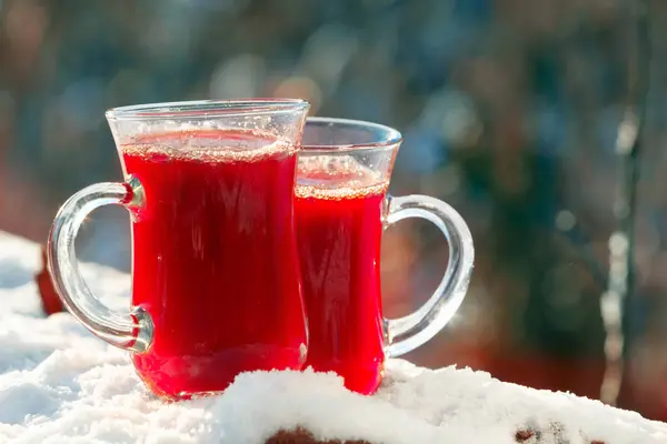Dos tazas con una bebida roja están en la nieve — Foto de Stock