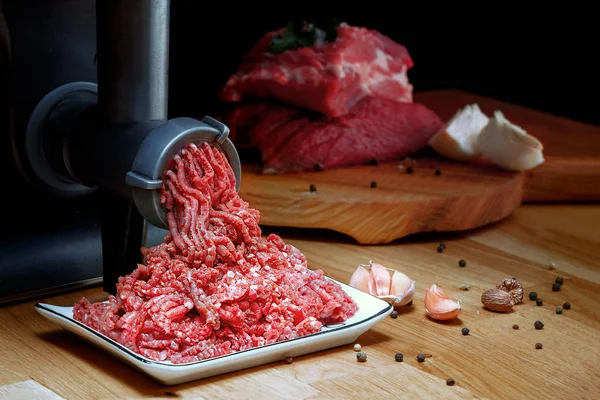 Minced meat coming out from grinder. Healthy homemade minced meat. Dark background. Horizontal view photo. Place for copyspace. — Stock Photo, Image