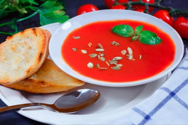 Fesleğen, tost ve domates ile beyaz bir tabak içinde domates çorbası. 