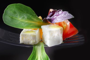 Peynir, domates ve fesleğen salata çatalı üzerinde. Yunan salatası