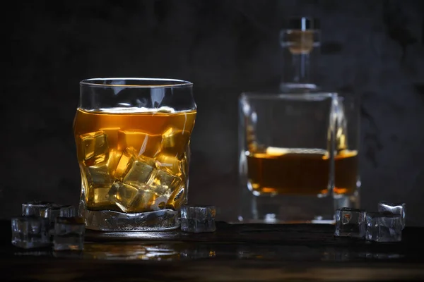 Alkohol pohárban jéggel és üvegben sötét háttér — Stock Fotó