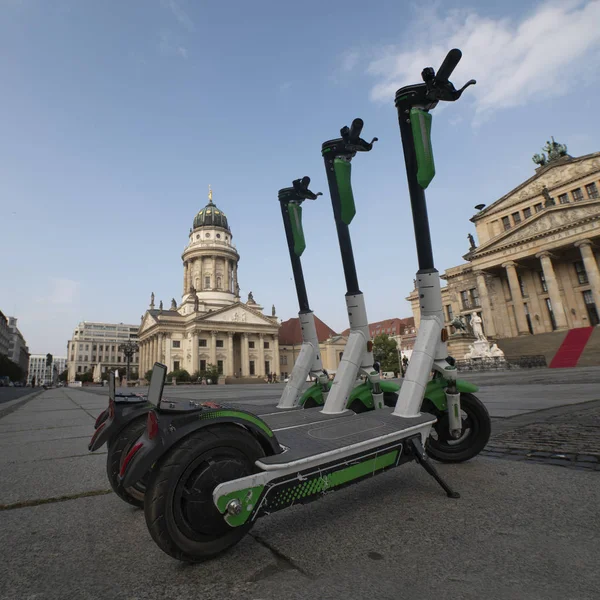 Elektrikli scooterlar Berlin 'deki jandarma parkına park edildi. Berlin Tiyatrosu 'nun arka planında birkaç tane e-scooter var. Güneşli yaz günü