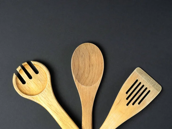 A variety of Cutlery and natural wood laid out on a black background. Concept of renewable sources and objects made of wood