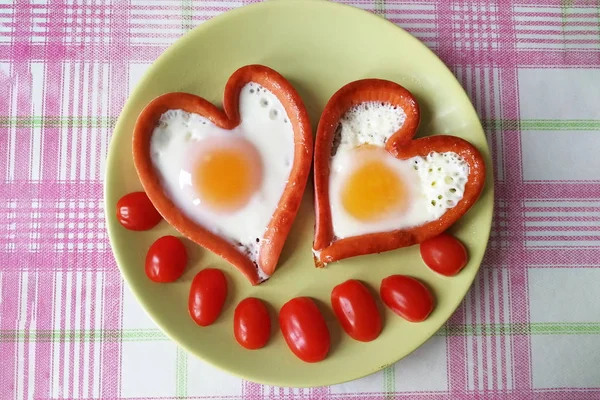 Top view of a dish of sausages and eggs in the shape of a heart. Decoration with cherry tomatoes. The concept of Breakfast for sweetheart — Stock Photo, Image