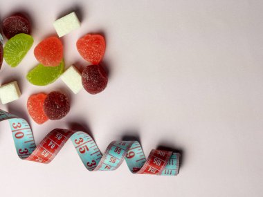 Gül arkaplanındaki şekerli bant ve marmelatı ölçmek. Üst görünüm, boşluk kopyala