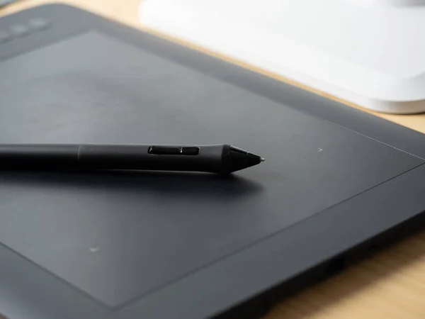 An electronic tablet with a graphic pen lying on it. The perfect tool for designers — Stock Photo, Image