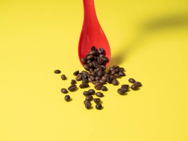 Kırmızı plastik kepçeden dökülen kavrulmuş kahve çekirdekleri