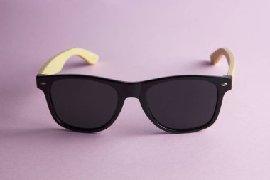 havalı siyah güneş gözlükleri ve pembe kağıt arka planda ahşap ördekler