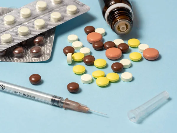 Шприц і різні ліки, вітаміни таблетки викладені на синьому фоні . — стокове фото