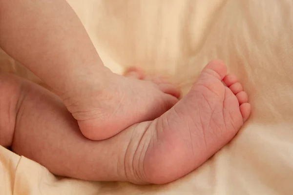 一个刚刚出生的婴儿的小巧可爱的脚踩在桃子上。 新生儿 — 图库照片