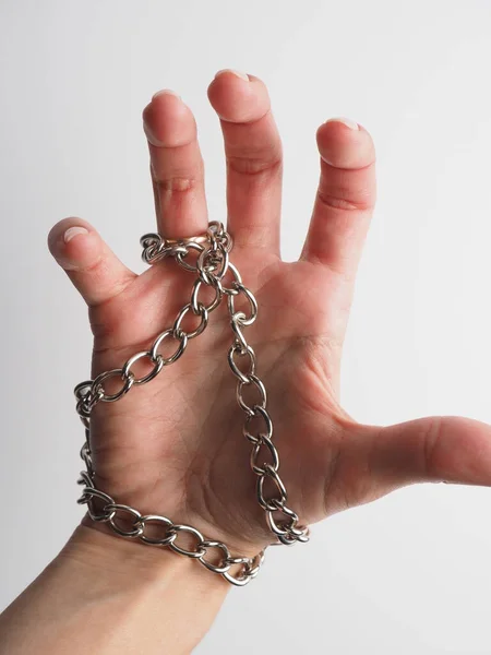 Mão feminina em um fundo leve entrelaçado com uma cadeia de metal . — Fotografia de Stock