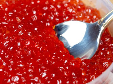 Parlak kırmızı havyar, içine metal kaşık batırılmış somon balığı. Lüks doğal lezzet.