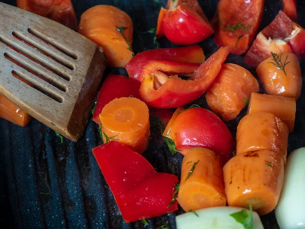 A friss zöldségeket serpenyőben sütik. Sárgarépa, édes paprika, hagyma. A vegetáriánus és egészséges élelmiszerek fogalma. — Stock Fotó