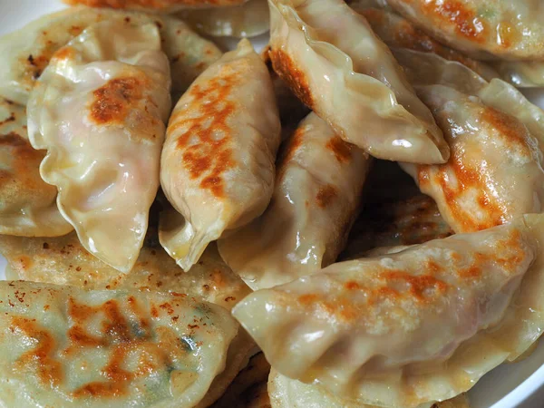 Hamur köfteleri tavada kızartılır. Çeşitli dolguları olan Asya yemekleri. Kızarmış Gyoza. Kapat, üst görünüm